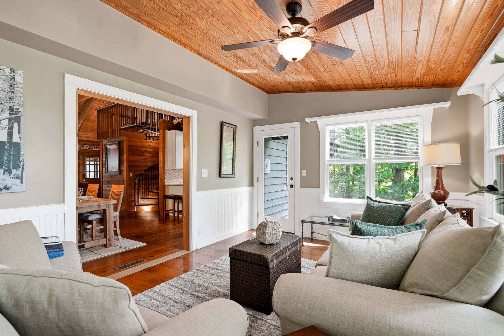 Bright sunroom with cream sofas and forest views