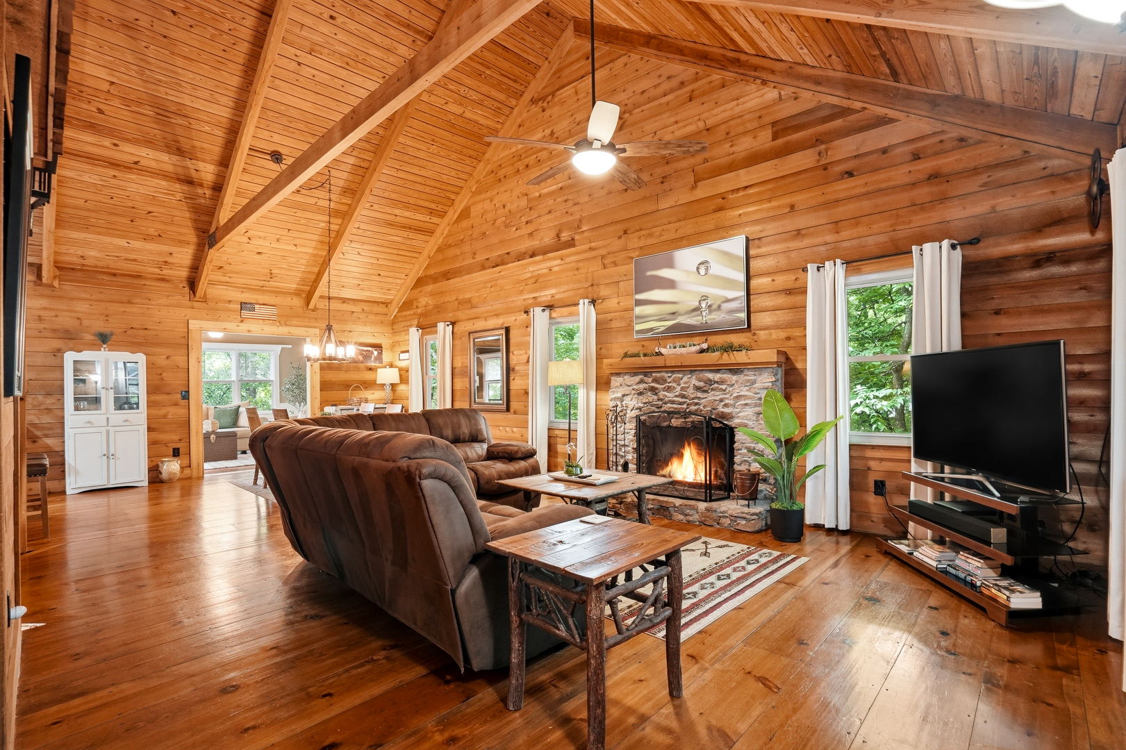 Living room with stone wood-burning fireplace and vaulted wood ceiling